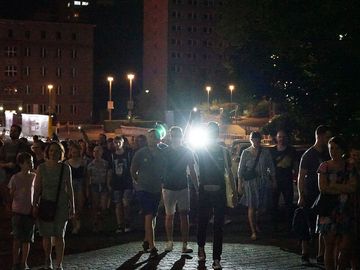 Eine Gruppe von Menschen erkundet das dunkle Gelände der ehemaligen Stasi-Zentrale mit Taschenlampen.