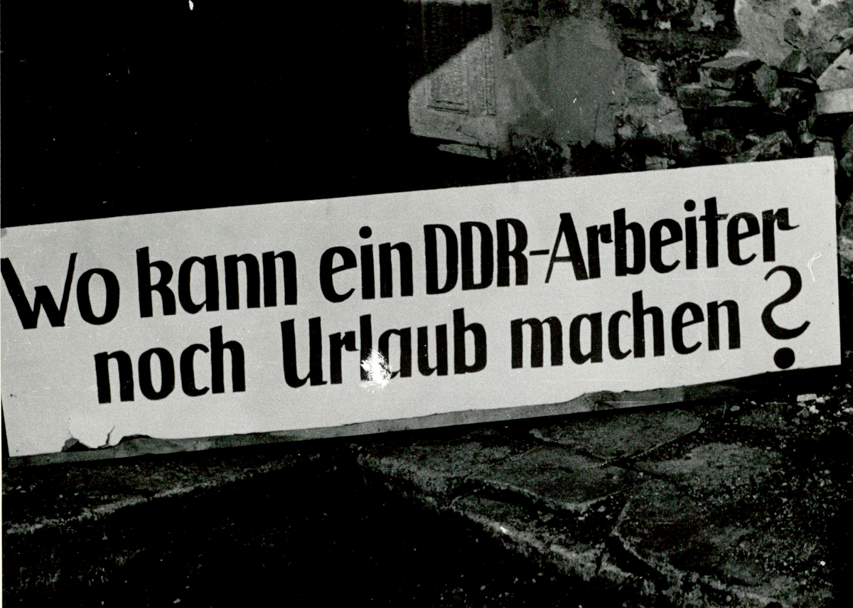 Plakat mit der Aufschrift "Wo kann ein DDR-Arbeiter noch Urlaub machen?".