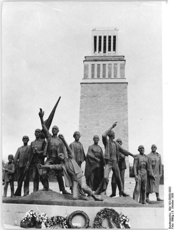 Auf dem Schwarz-Weiß-Foto ist das Buchenwald-Mahnmal vor dem Glockenturm zu sehen. Das Denkmal besteht aus elf Bronzefiguren, die KZ-Häftlinge darstellen.