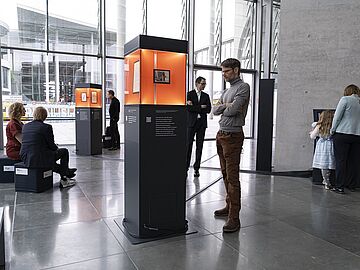 Mehrere Personen stehen und sitzen in der Ausstellung "Alles Wissen Wollen" im Bundestag.