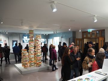 Besucherinnen und Besucher am Tresen der Ausstellung "Einblick ins Geheime".