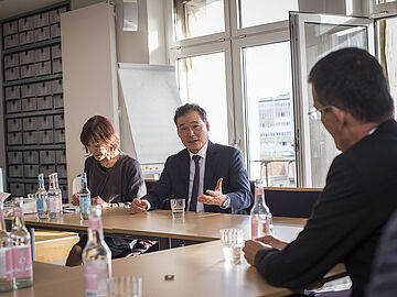 Kim Yung Ho sitzt an einem Tisch und spricht mit Mitarbeitern des Bundesarchivs.